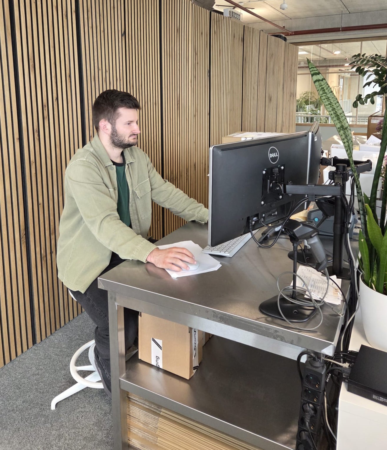 Man working at a standing desk with a computer in an office setting Man working at a standing desk with a computer in an office setting